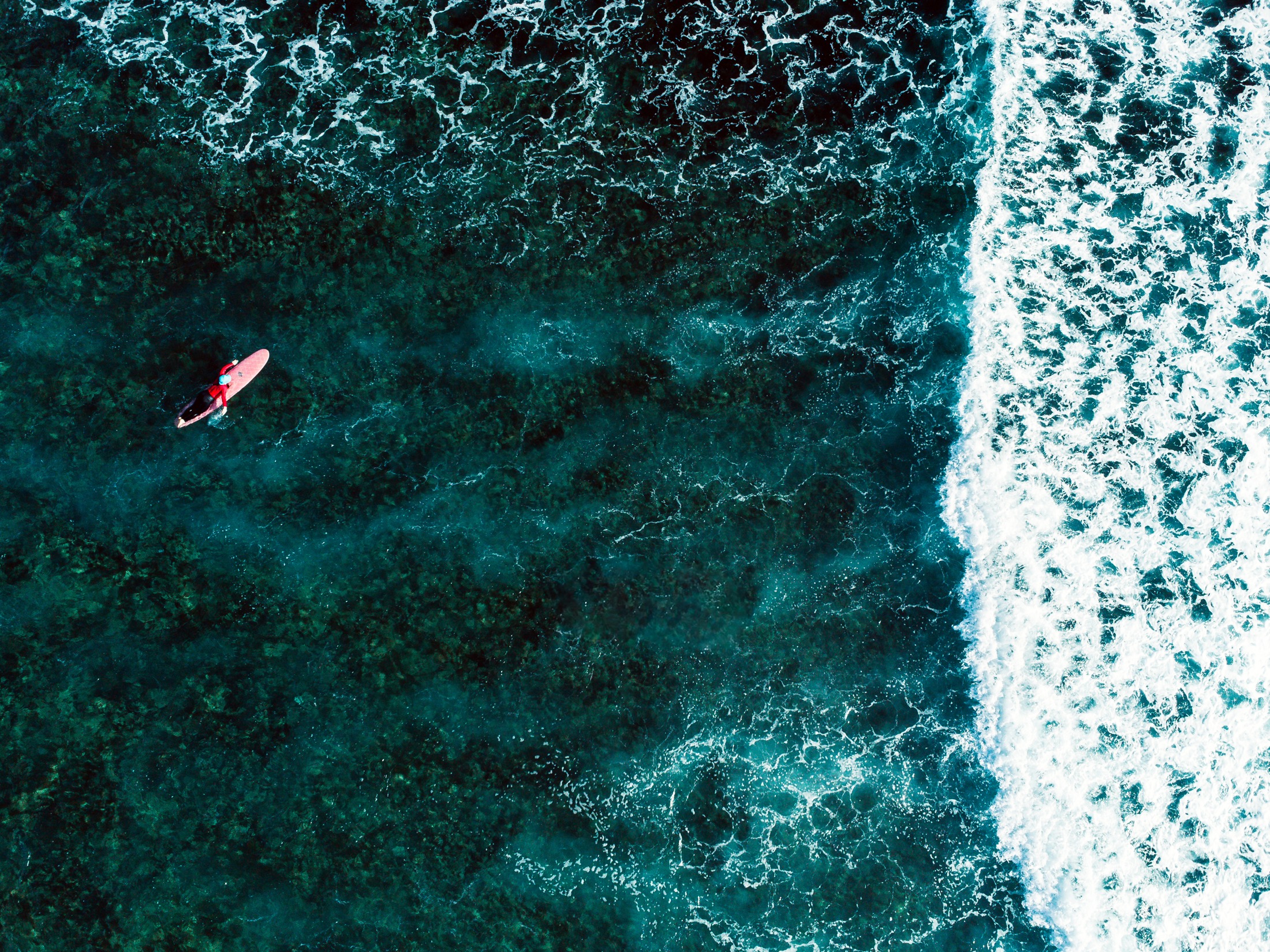A lone surfer meets a turquoise wave at Cloud 9, Siargao